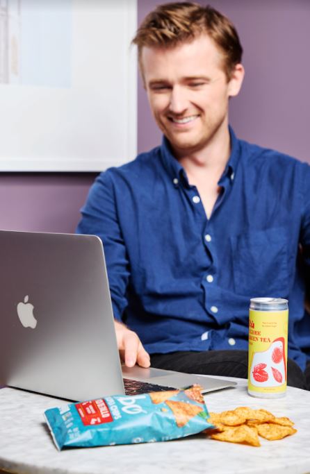 Man eating snacks while watching his laptop 