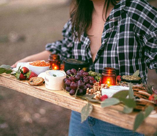 Ten New Ways to Satisfy Your Snacking Needs Woman carrying a wooden board of cheese and snacks