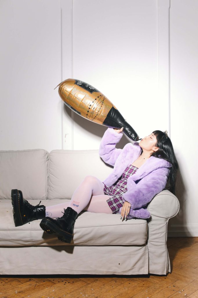 Woman pretending to drink from a champagne balloon bottle