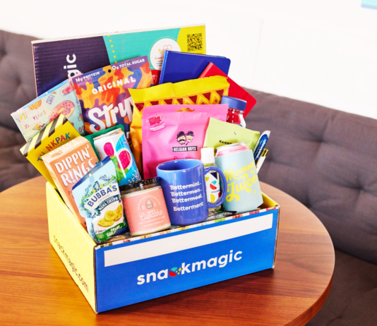 25 Memorable Corporate Gift Boxes for Employees, Clients, and More A fully stacked SnackMagic box full of treats and gifts on a conference table.