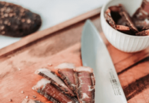 Introducing Biltong: A Favorite South African Snack Biltong being prepared alongside a chef's knife.