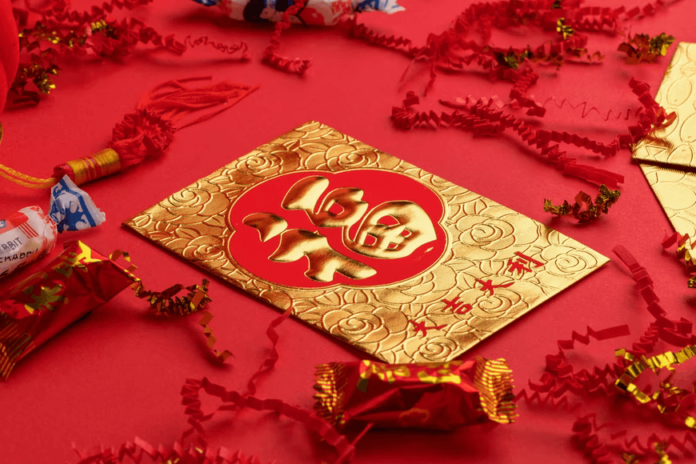 A red and gold card on a table decorated in red for Lunar New Year