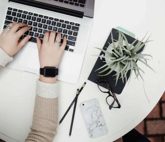 10 Onboarding Gift Ideas for Employees Who Just Joined the Company An employee logging in to a remote work day with nearby office supplies and a plant nearby.