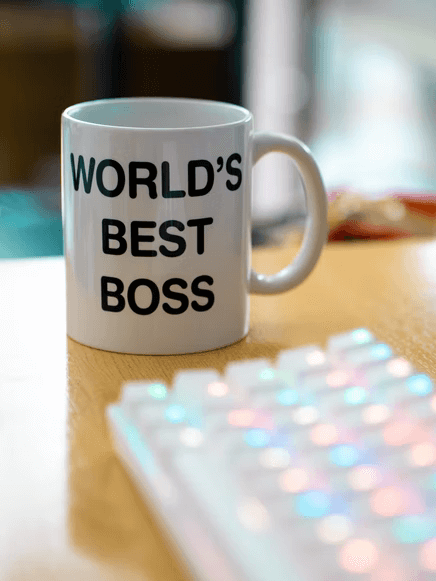 A world's best boss mug alongside a multicolored keyboard.