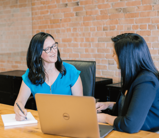 5 New Corporate Gifting Trends in 2024 Two women in an office having a pleasant conversation at work.