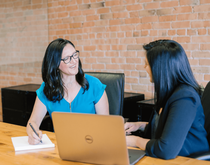 Two women in an office having a pleasant conversation at work.