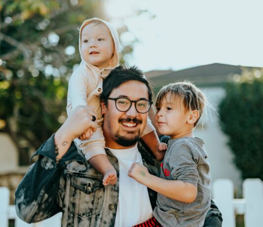5 Father’s Day Gifts for the New Millennial Dad A young father smiling with his two young children.