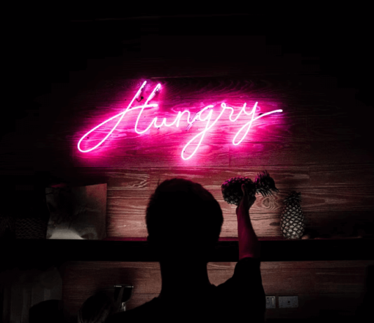 7 Themed Snack Boxes That Can Be Easily Ordered Online A neon sign in a dark bar, spelling out "Hungry" in looping cursive.