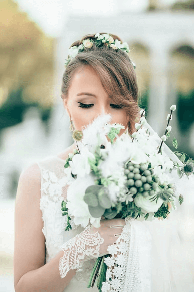 A beautiful bride on her wedding day smelling her bouquet of flowers. 