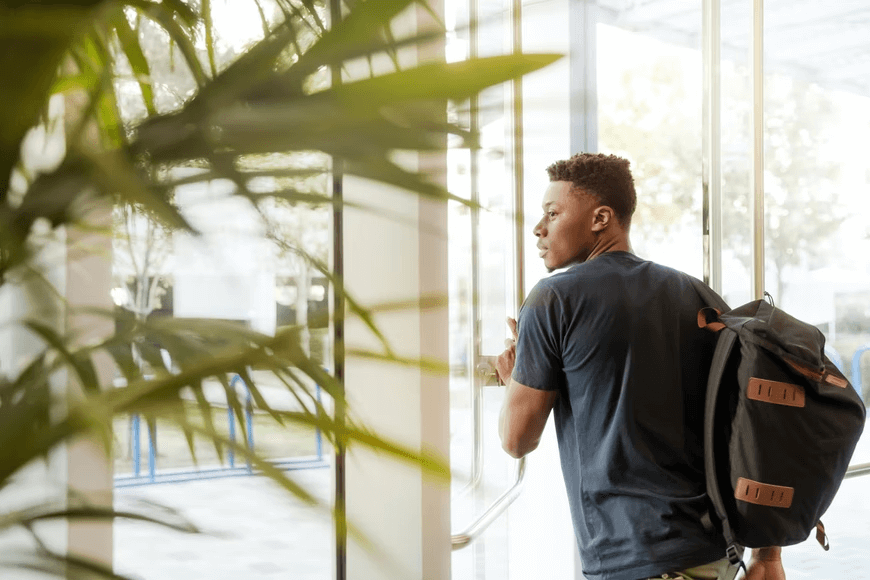 A student walking through a doorway on his way to class. 