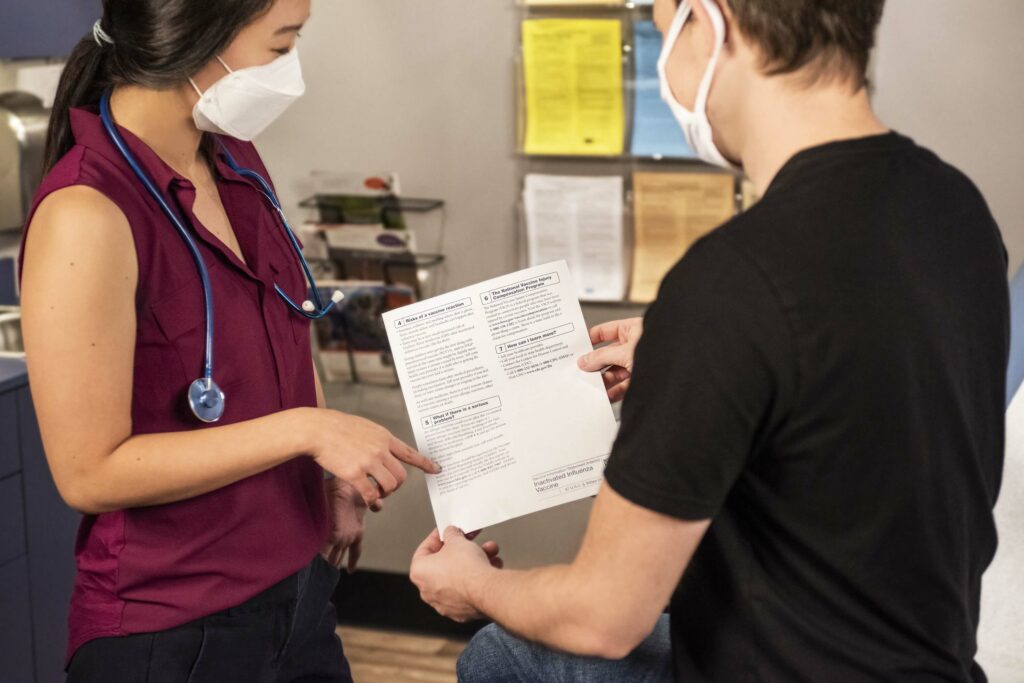 A healthcare worker and patient looking over a sheet with medical information.