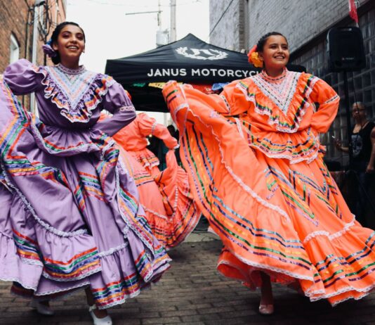 4 Unique Ways to Celebrate Hispanic Heritage Month Two dancers in a parade wearing traditional dress.