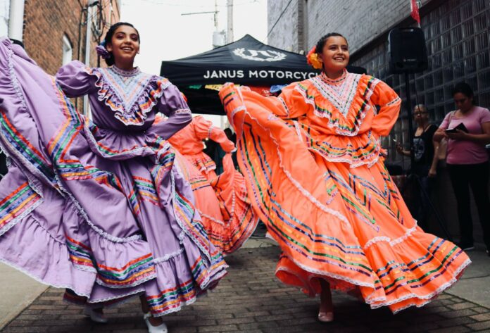 Two dancers in a parade wearing traditional dress.